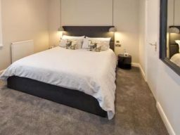 Blackbird Luxury Accommodation Suite 7 Brown leather sofa with decorative pillows and a lamp in a light-filled room.