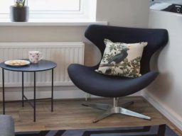 Blackbird Luxury Accommodation Suite 7 Brown leather sofa with decorative pillows and a lamp in a light-filled room.